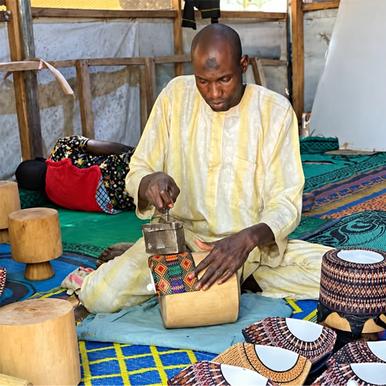An artisan tooling a leather drum